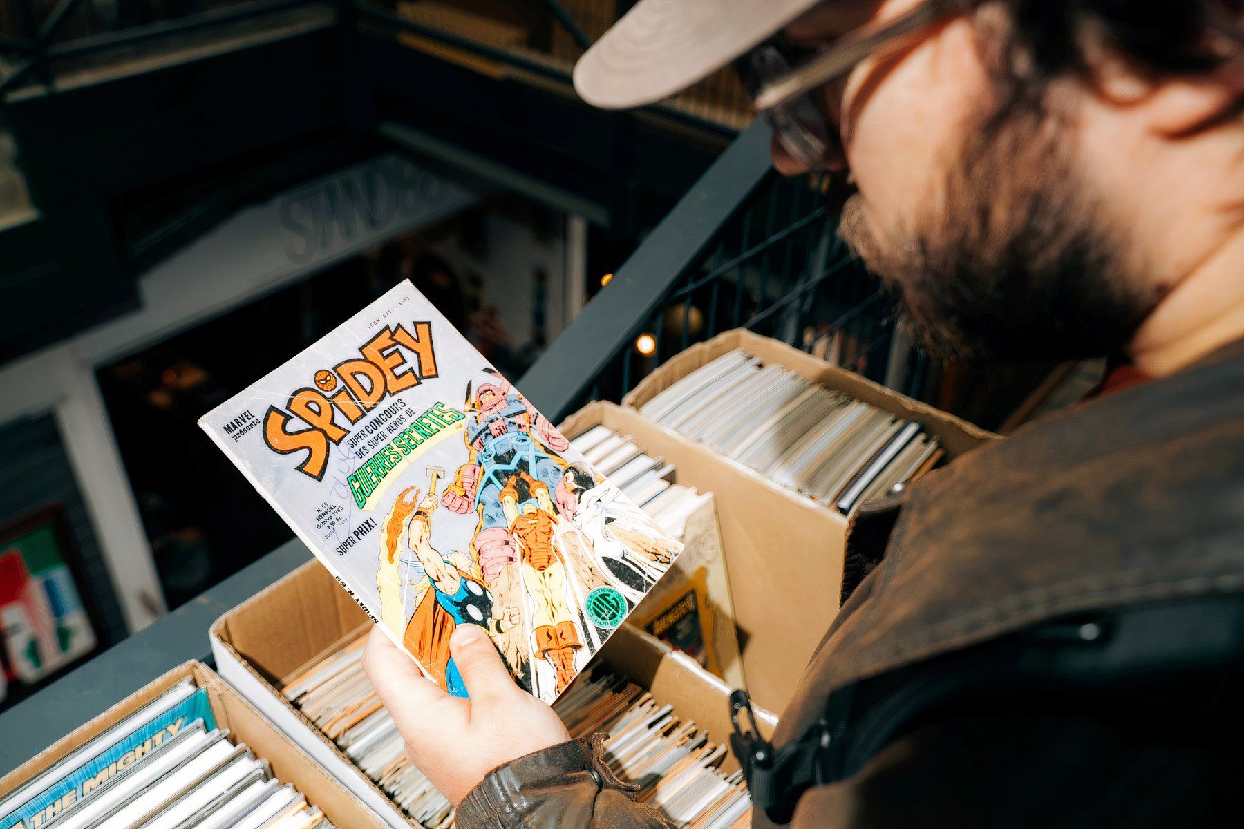 Person flipping through a bin of comic books featuring a Spider-Man issue