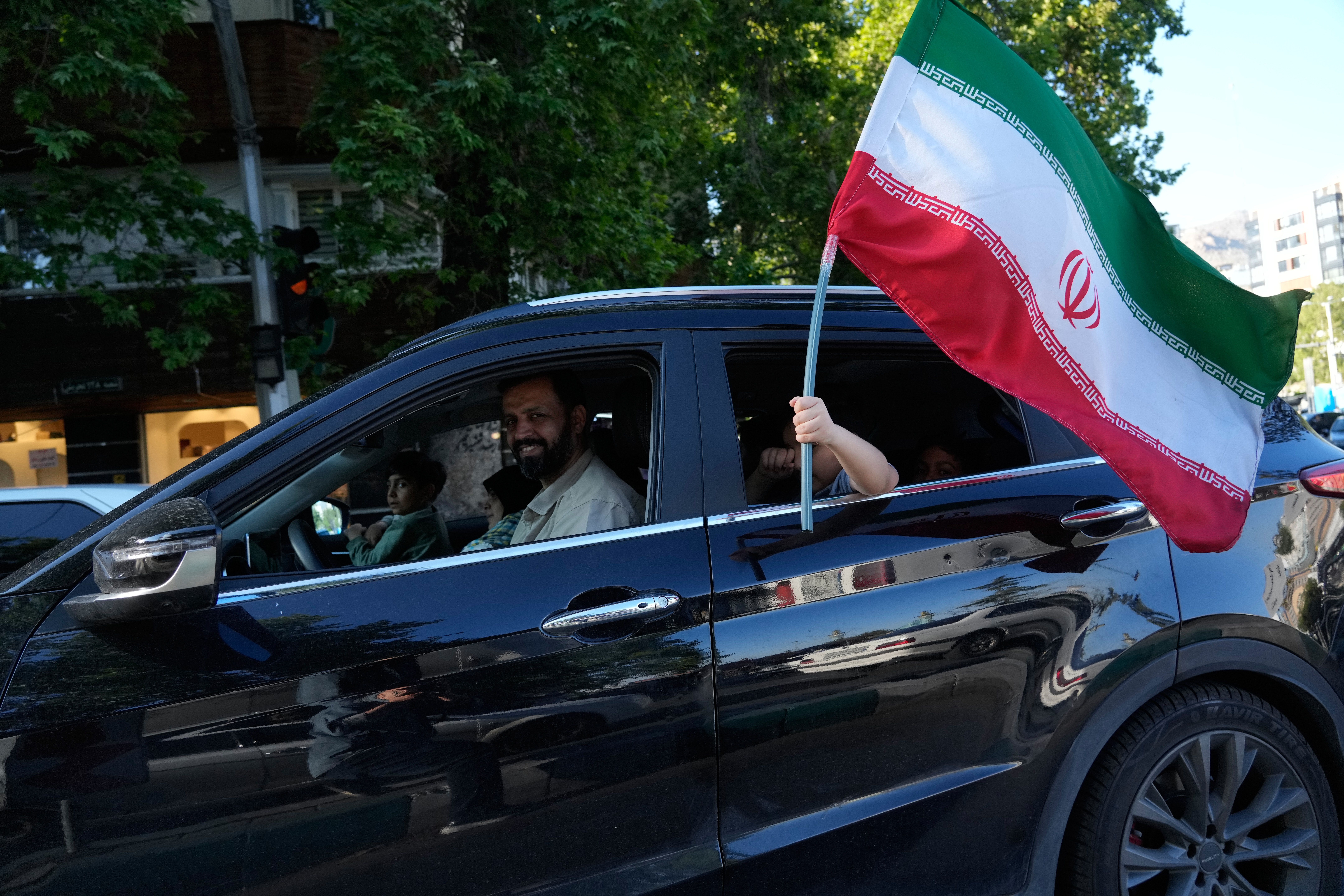 A child holds an Iranian flag through the window of a vehicle in Iran.