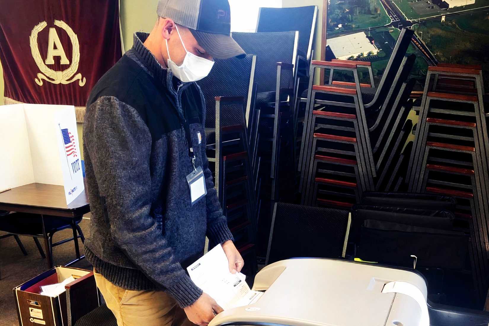 Spc. Nathan Stepp feeds absentee ballots into a voting machine in Amery, Wisconsin, during a 2020 special election.