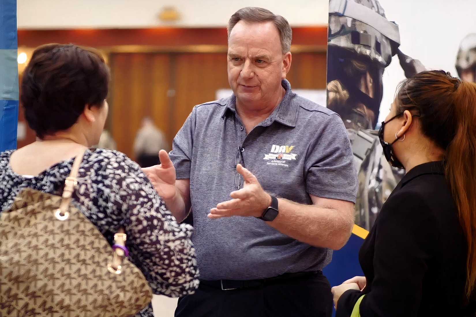 A DAV representative speaks with two attendees at a veterans career fair.