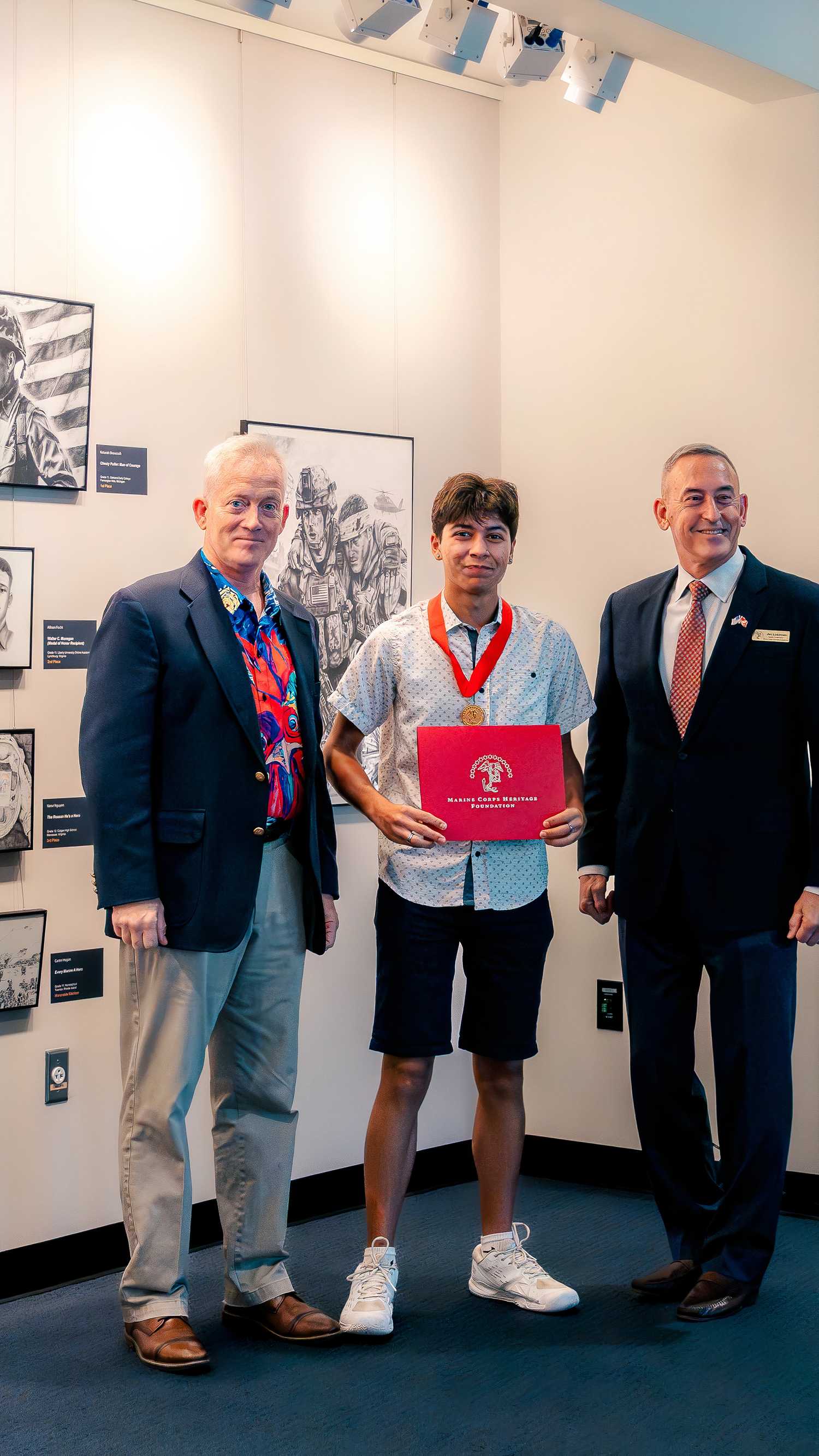 Marine Corps Artist in Residence Kris Battles, student artist Storm Alho and retired Maj. Gen. James W. Lukeman pose after the award ceremony.