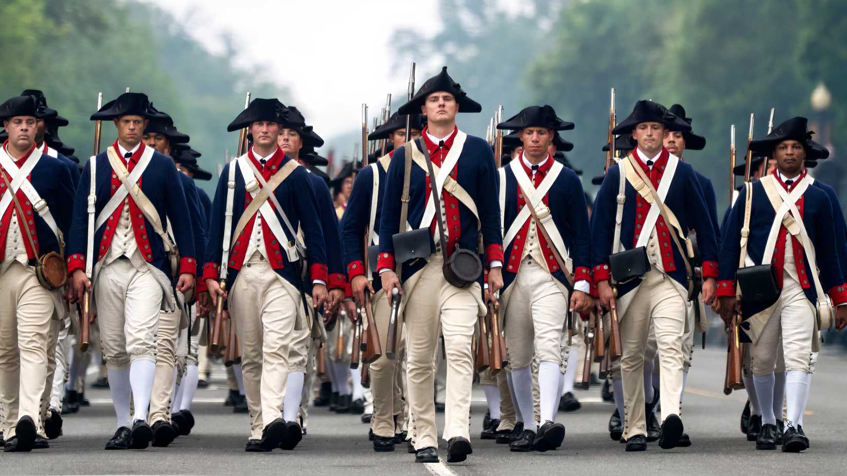 Service members dressed as Revolutionary War veterans march in formation during Army’s 250th Birthday Parade