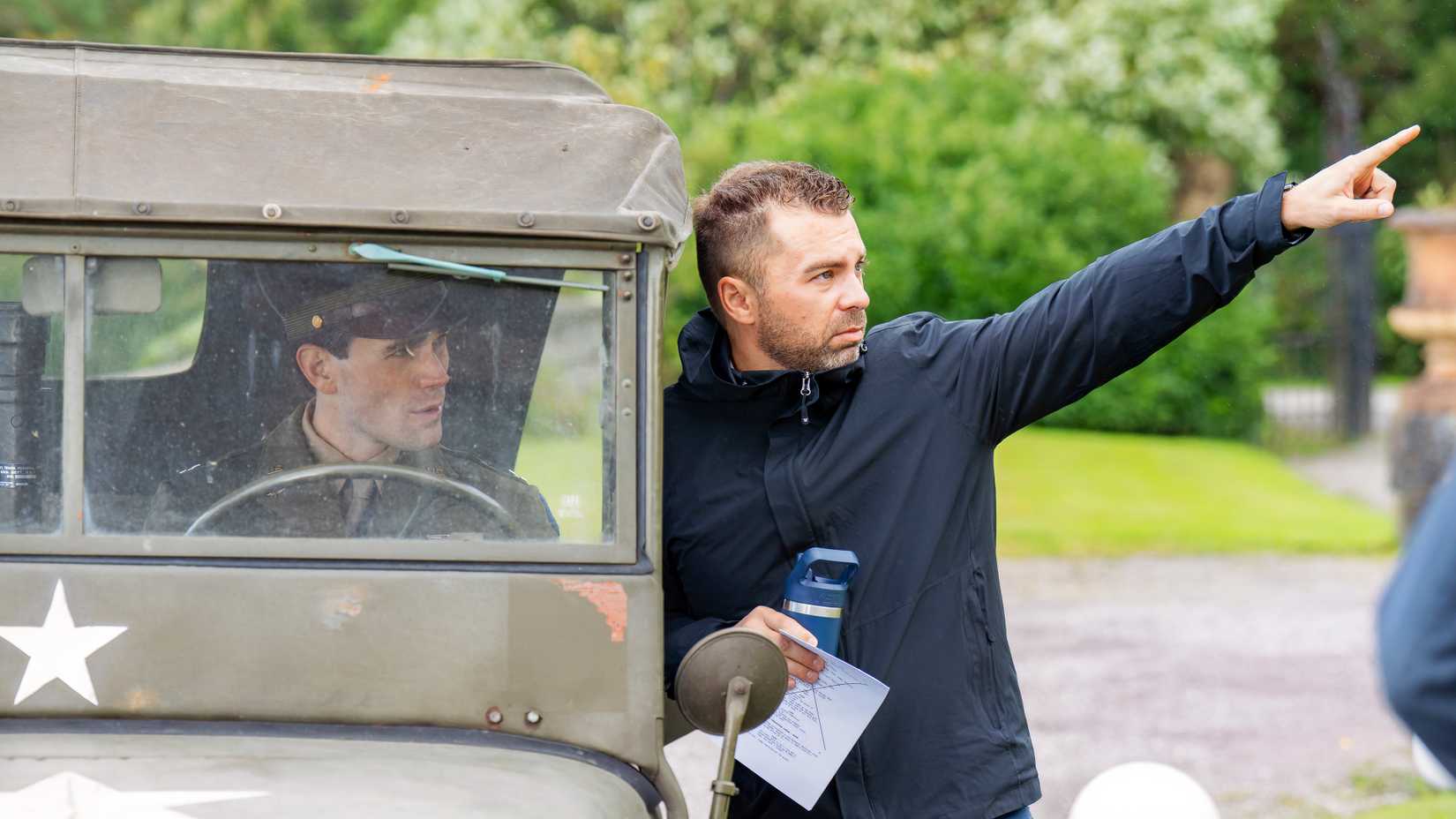 Director Aaron Burns gives direction to KJ Apa from beside a World War II-era military jeep during filming of JIMMY.