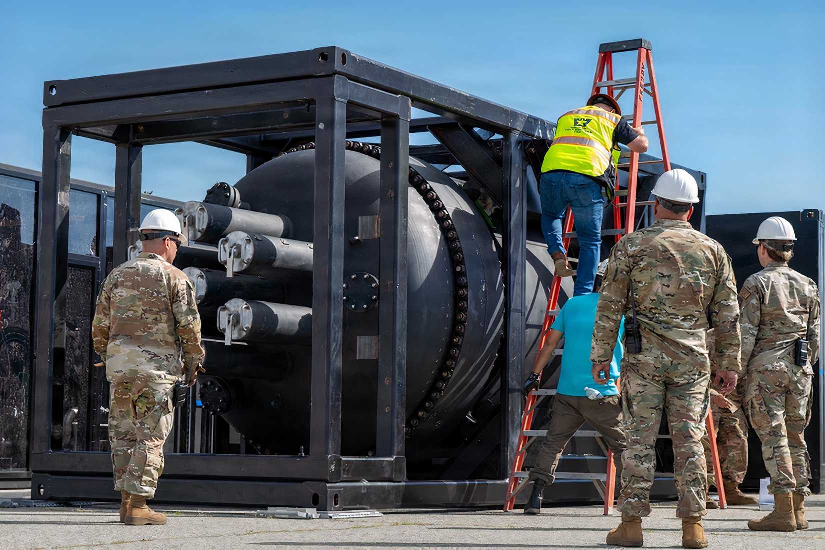 Airmen and civilian contractors prepare a containerized nuclear power reactor for transport aboard a C-17 Globemaster III.