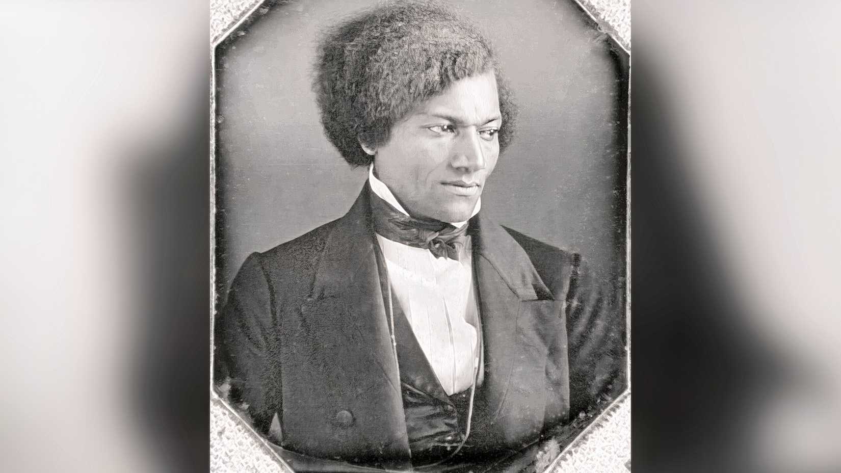 A black-and-white daguerreotype portrait of Frederick Douglass in formal clothing.