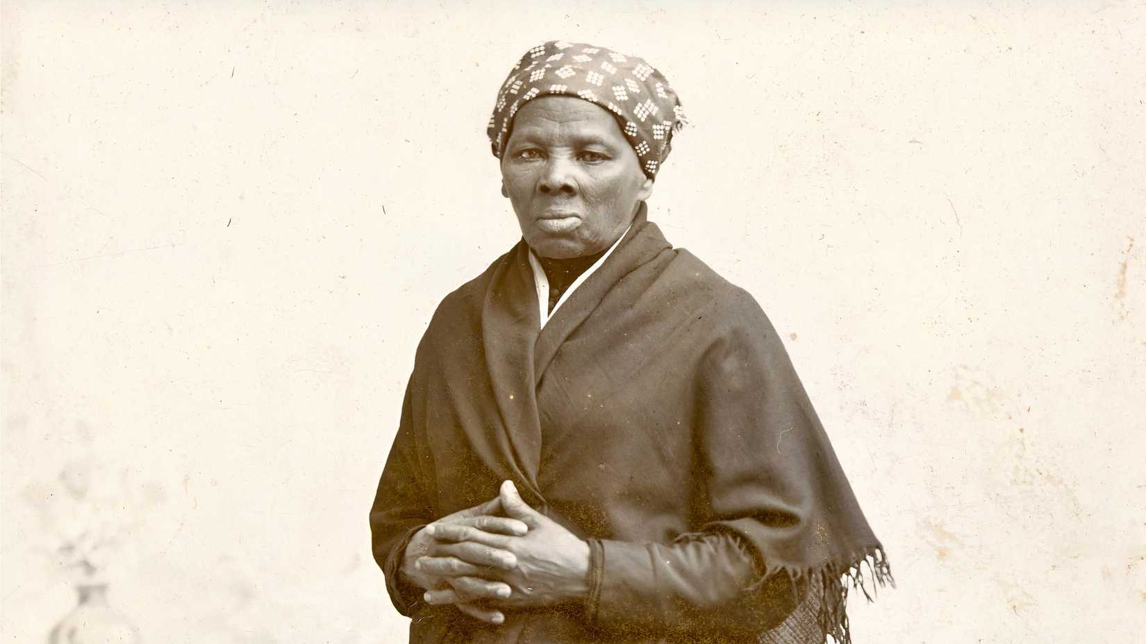 A black-and-white portrait of Harriet Tubman wearing a head covering and shawl.