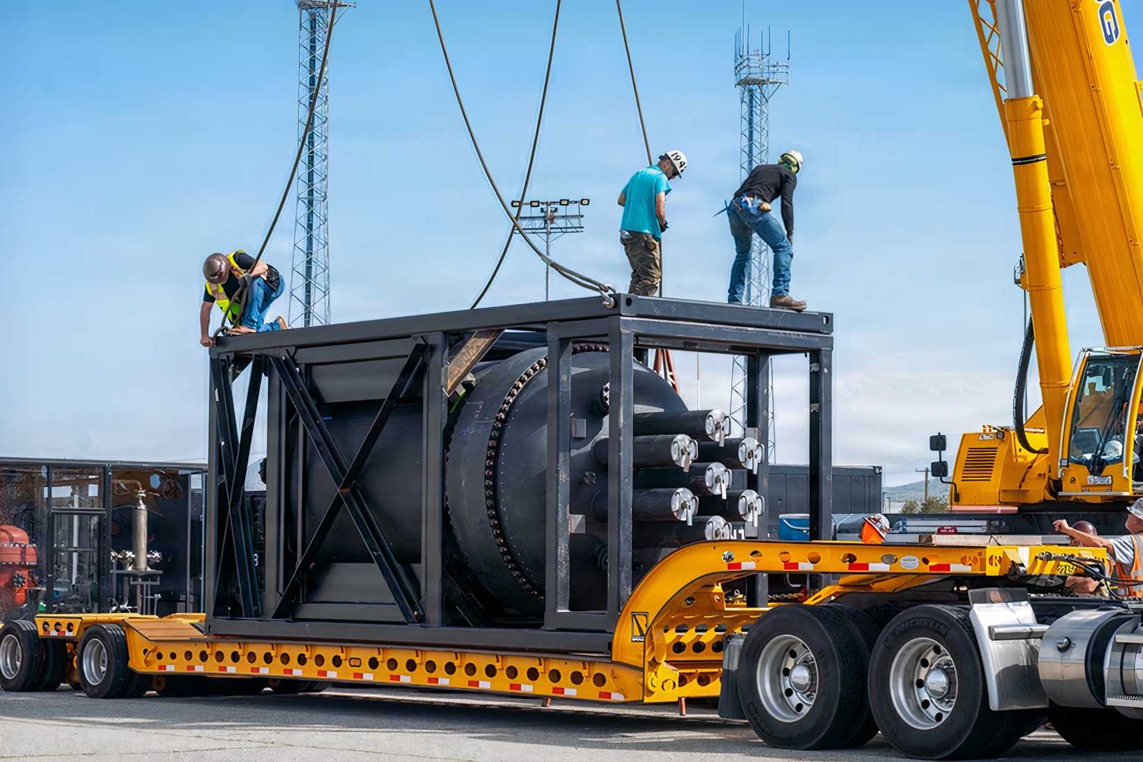 A crane and transport crew position a containerized nuclear power reactor for military airlift during a Defense Department and Energy Department demonstration.
