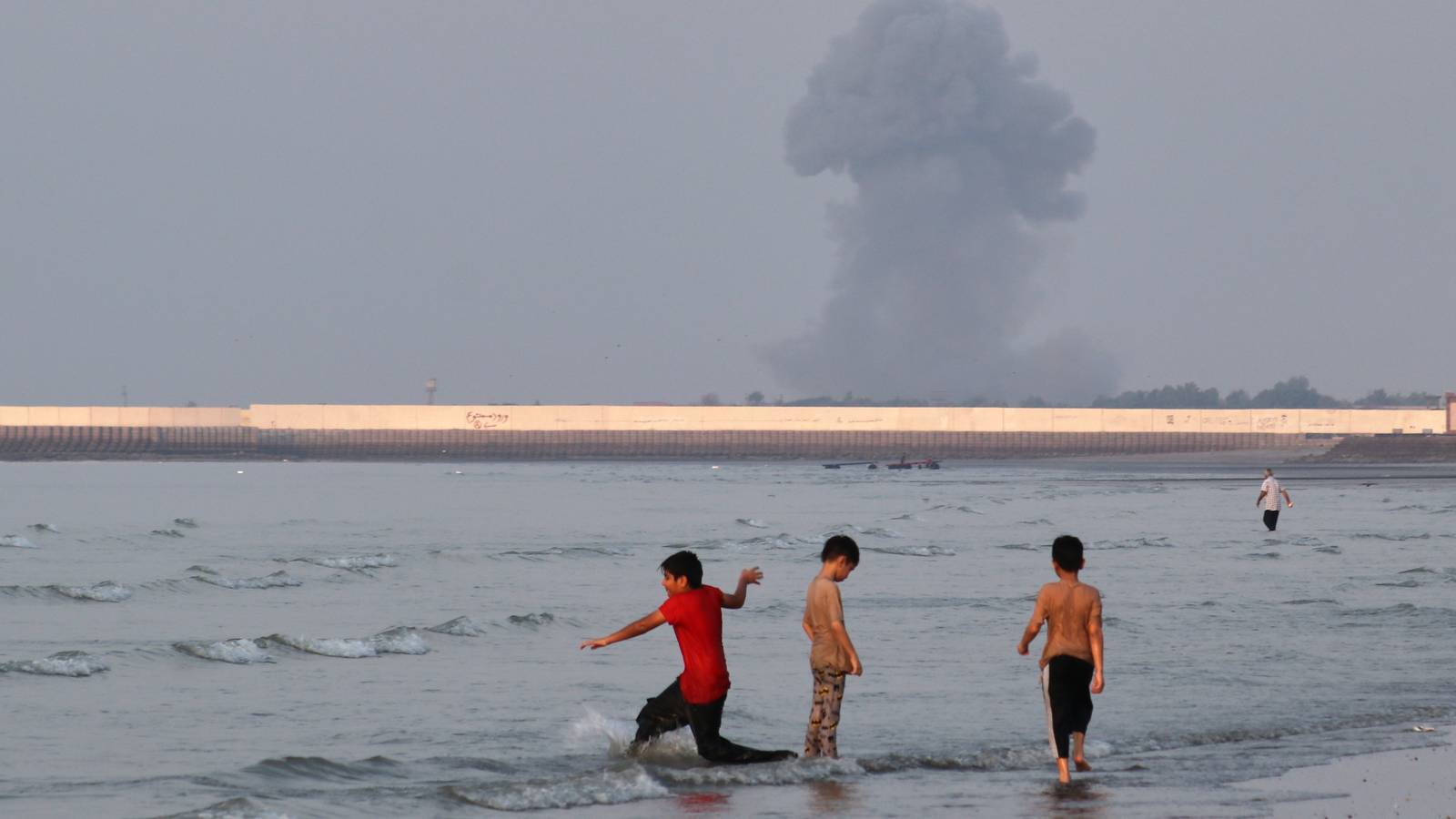 Three boys play in the shallow waters of the Strait of Hormuz.