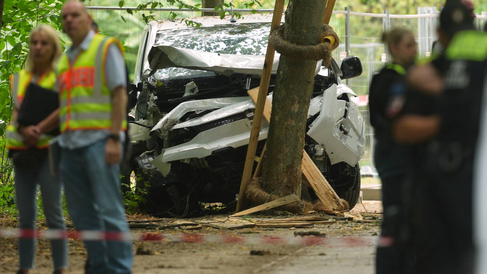 Police officers stand near a vehicle crashed into a tree.
