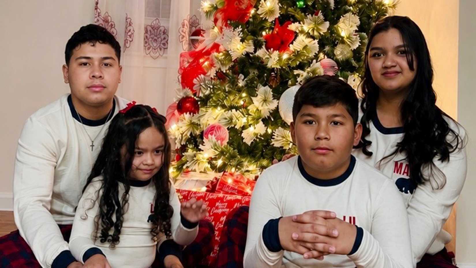 Army Sgt. Hedár Leonel Turcios Juárez and his wife, Cristy Maryori Villafranca Trejo, pose with their two children in front of a decorated Christmas tree.