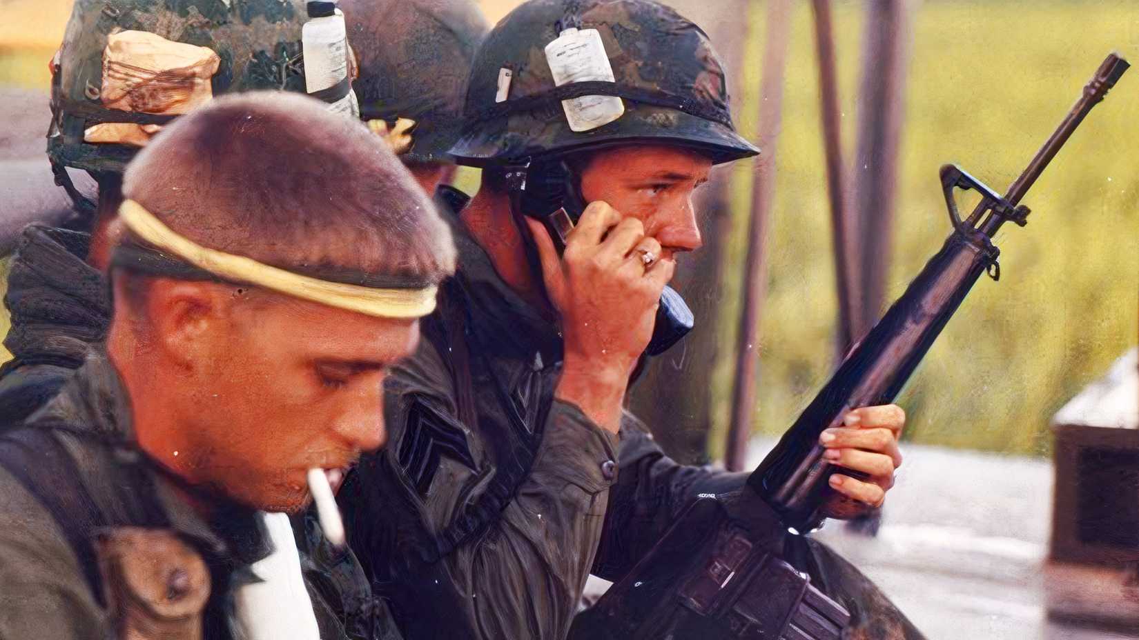 A U.S. soldier speaks on a field telephone while another holds an M16 rifle during the Vietnam War.