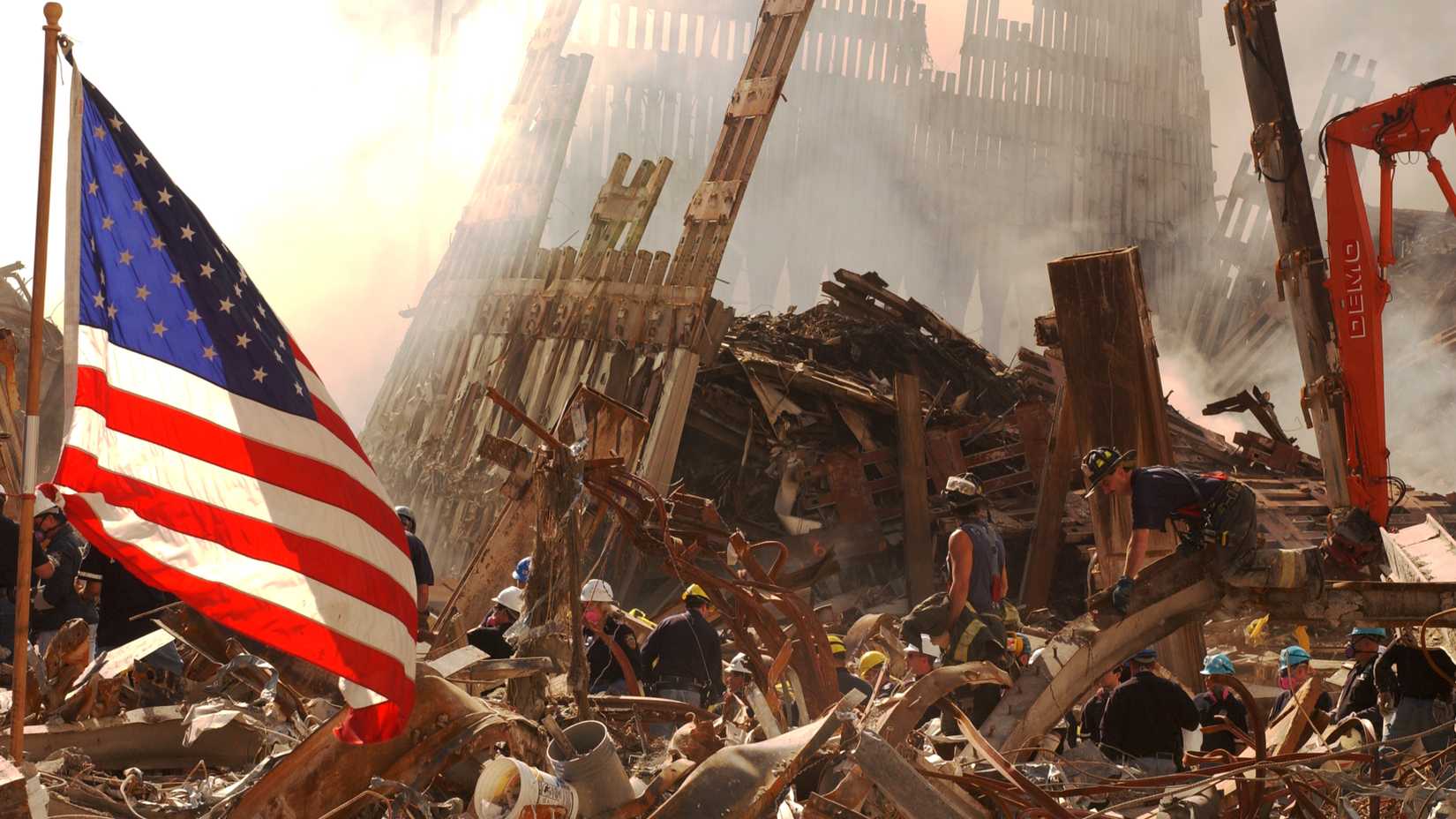 An American flag hangs above rescue workers searching through the wreckage of the World Trade Center at Ground Zero on Sept. 19, 2001. (FILE).