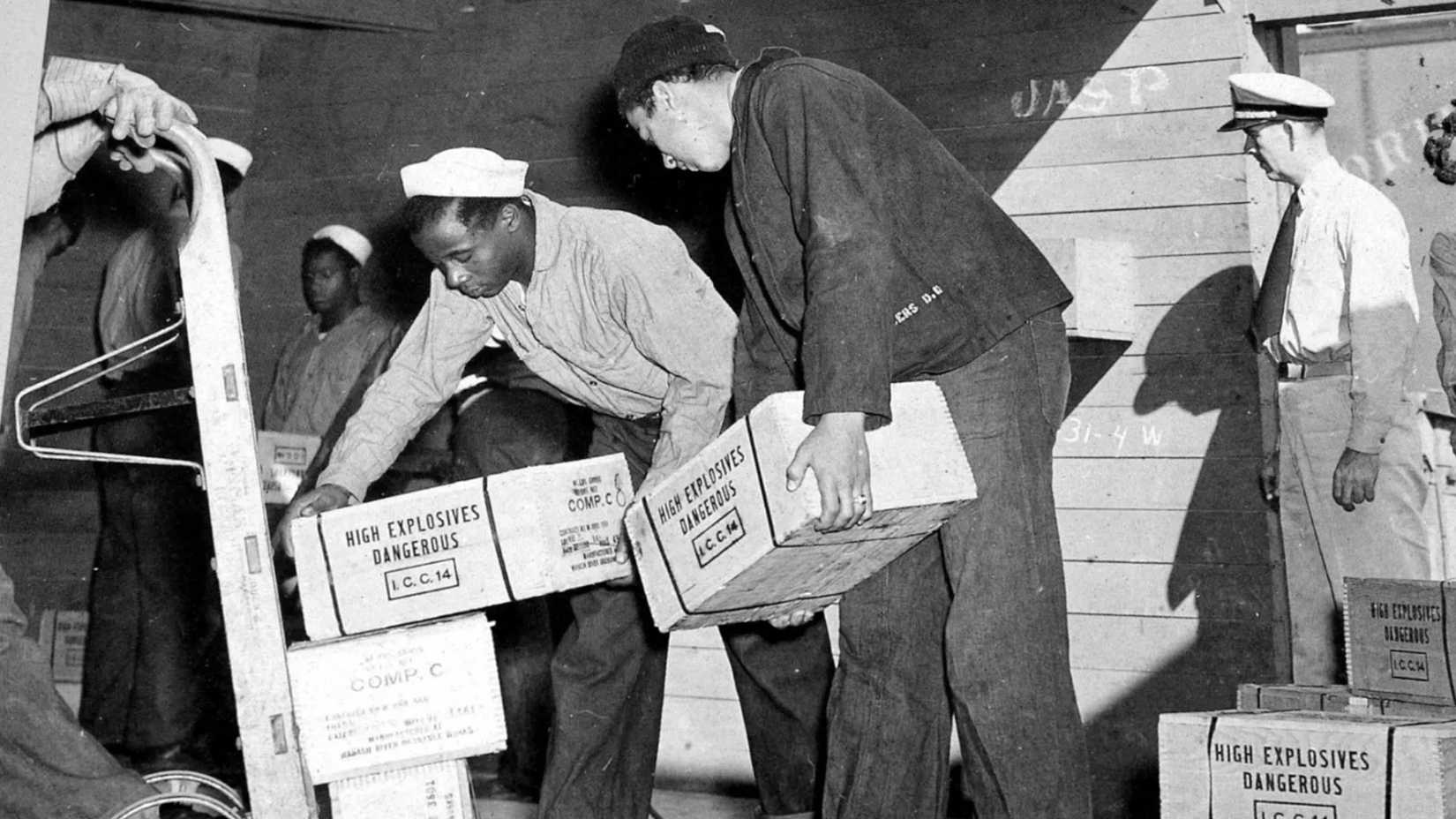 Black sailors load boxes marked “High Explosives Dangerous” at the Port Chicago Naval Magazine during World War II.