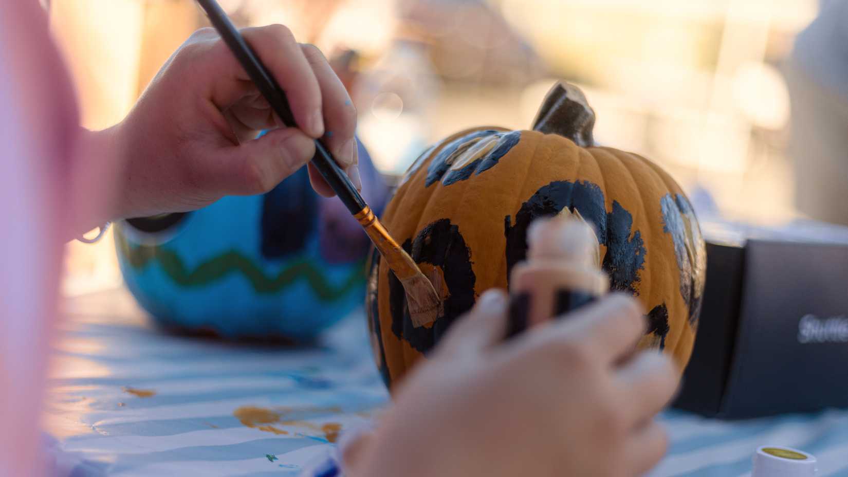 A Marine paints a small pumpkin during a Halloween Trunk-or-Treat event at Camp Pendleton.