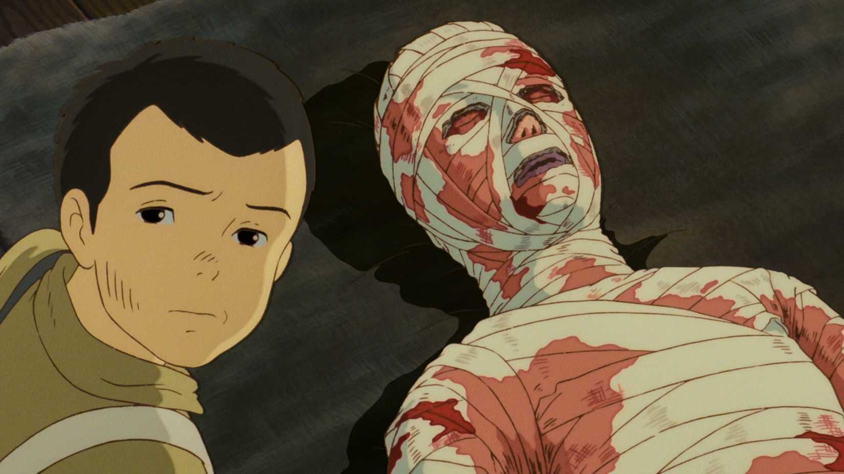 Seita looks toward a severely burned and bandaged patient lying on a bed in a disturbing scene from Grave of the Fireflies.